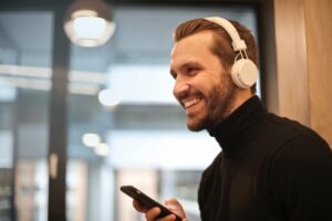 man wearing white over the ear headphones listening to phone