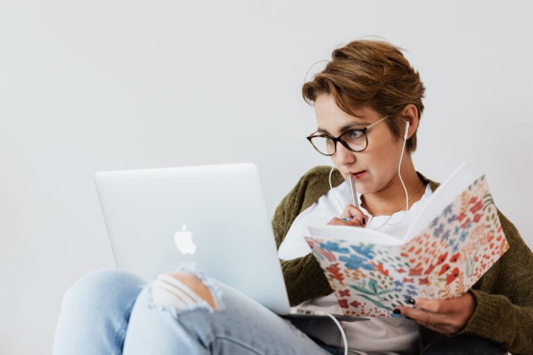a woman with short hair on her mac writing in her notebook