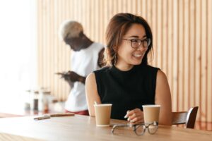 an asian woman smiling while drinking coffee in the office.