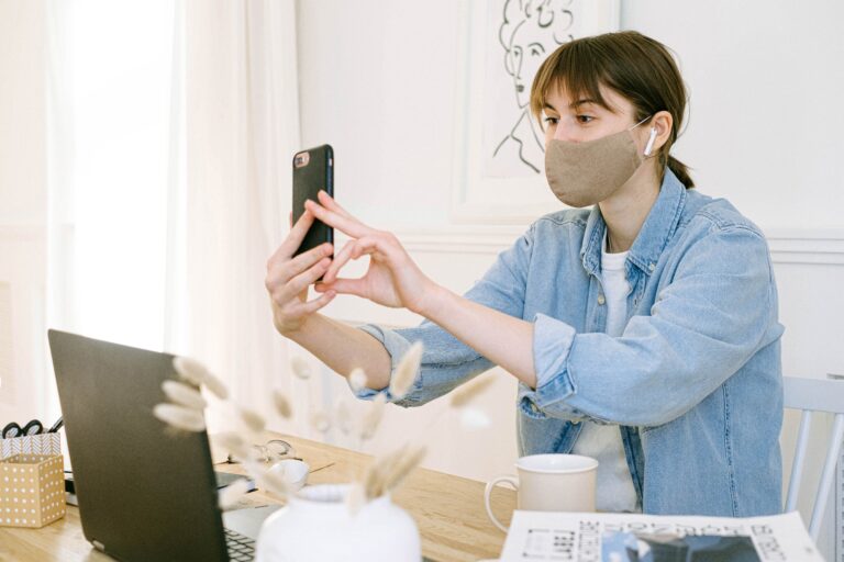 a woman in the office wearing a mask while working and facetiming.